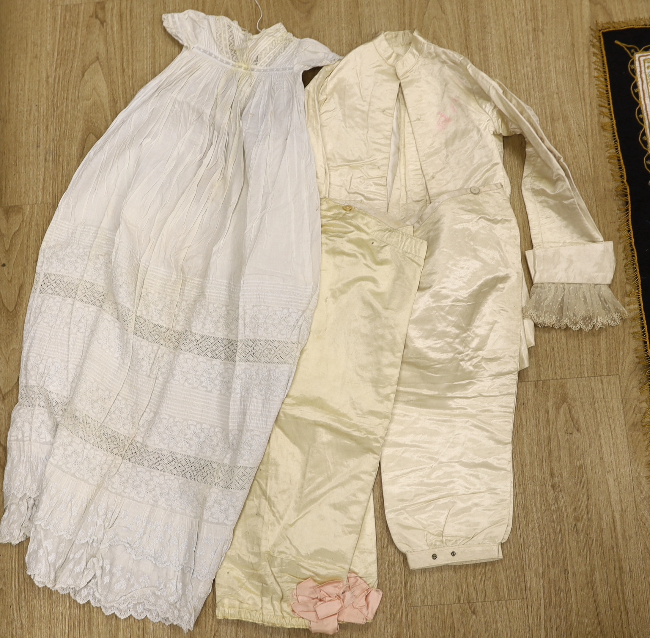 An embroidered Indian felt cover, a cream satin pageboy outfit, a white work christening gown, a silk shawl, a knitted silk shawl and a length of brocade